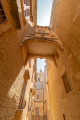 A link between sandstone buildings in a narrow alley in the old capital of Malta, Mdina