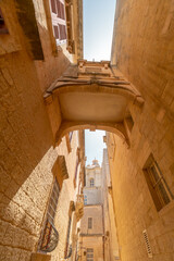 A link between sandstone buildings in a narrow alley in the old capital of Malta, Mdina