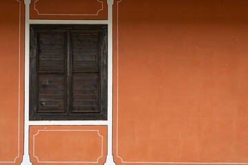 Painted in orange wall of a house and a wooden window