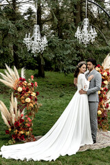 Beautiful wedding couple hugging and kissing at the wedding ceremony on the background of the forest