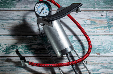 Silver foot pump for car and bicycle tires, on a green wooden background