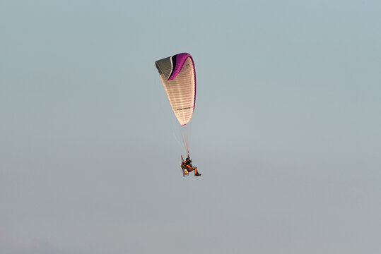 Warsaw, Poland - July 15, 2020: Paramotor flight at sunset. Active recreation with adrenaline. A paraglider in the air.