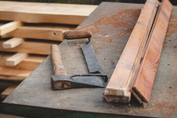 Traditional woodworking using old and hand tools such as an axe and planer stored on an iron table with wooden logs