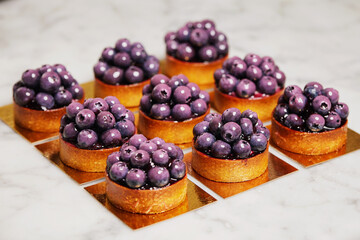 Closeup group of delicious tarts with berries served on golden paper. Restaurant sweet bakery.