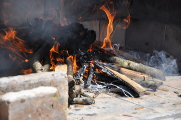 Vintage fireplace. Warm Hearth taken closeup. Garden fireplace with a chimney, made of old bricks, with a fire inside.Outdoor oven made of white brick with a wooden bucket. Rural summer kitchen.