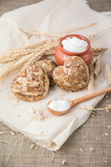 Beautiful heart-shaped gingerbread cookies are arranged with sour cream. Delicious cookies with spikelets