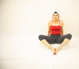 pretty athletic asian woman in gray sportswear, red blouse, sitting meditating after exercising with feet together, on white background