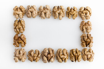 Frame of peeled walnuts flat layed in the shape of rectangle isolated on white background. Copy space. Top view.