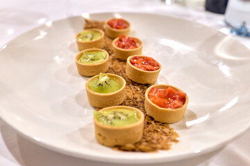 White round plate with fruit tartlets or small pies
