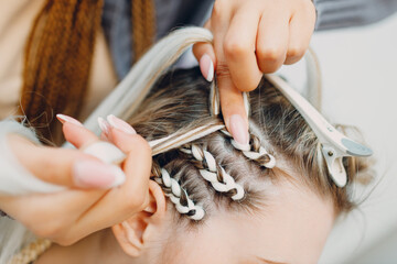 Hairstylist braided afro braids dreadlocks kanekalon pigtails hair of female client in barber salon. - obrazy, fototapety, plakaty