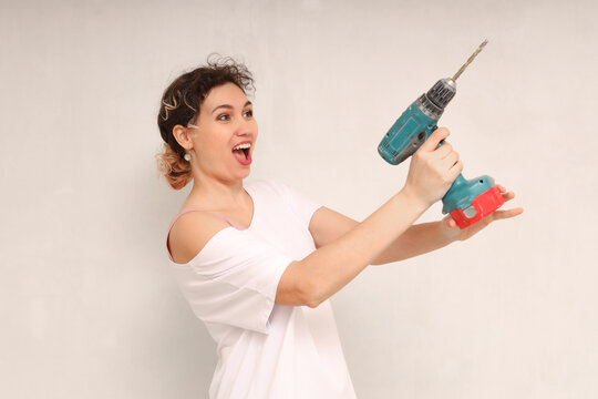 Laughing young woman hold electric drill.