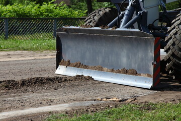 Fototapeta na wymiar Heavy bulldozer shovel levels asphalt surface. Asphalt laying on rural road. Industrial machinery. renovation of the road side