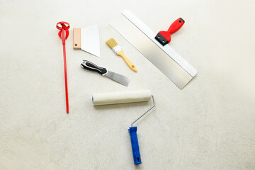 Paint set: roller, brush, spatulas, whisk for plaster on the concrete floor, close-up. Repair tools lies on floor