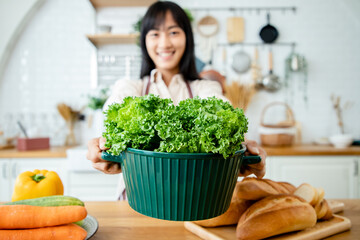 Close up, Beautiful woman holding organic groceries looking positive and happy standing and smiling with a confident smile showing teeth in kitchen. Chef at home