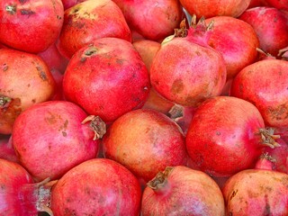 Fototapeta na wymiar background of many red ripe pomegranates for sale at greengrocer