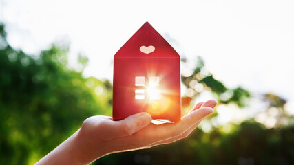 Red paper house model in hand. Eco friendly home, construction, mortgage, ecology, loan concept. Zero waste, organic, sustainable lifestyle. Trendy eco home in nature. Selective focus. Copy space