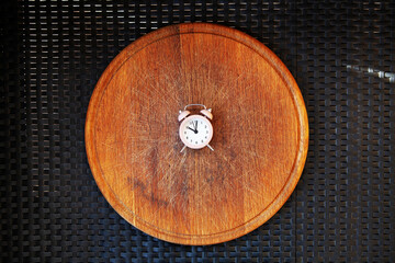 Round wooden cutting board with retro alarm clock. Intermittent fasting IF diet concept with 8-hour clock timer for eating nutritional. Intermittent fasting concept, ketogenic diet, weight loss