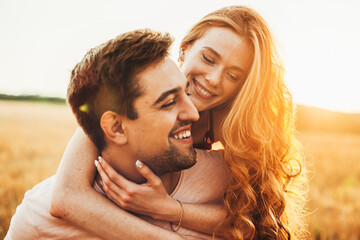 Portrait of a red-haired girl happy with time spent with her boyfriend outdoors, hugging him from...