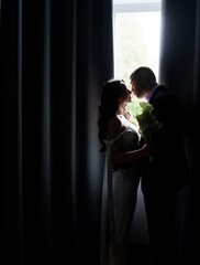 Silhouette of a beautiful newlywed couple on the background of the window in a hotel room. High quality photo