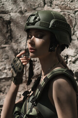 Military girl in uniform near a stone wall during the day. Portrait