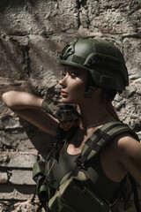 Military girl in uniform near a stone wall during the day. Portrait