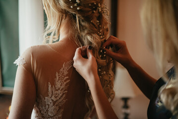 Bridesmaids helping bride getting dressed for the wedding ceremony.