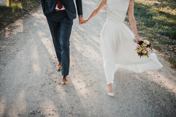 Fototapeta premium Bride in beautiful white wedding dress with bouquet and elegant groom in suit at happy wedding day. 