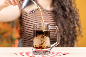woman with curly hair sitting pouring coffee into a transparent mug