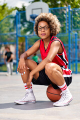 Fototapeta premium girl with afro hairstyle with a ball on a basketball court