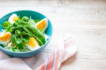 A plate of summer salad on a wooden background. Salad with spinach, basil, cabbage and eggs. Food, healthy breakfast