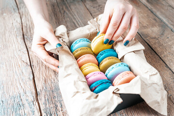 Girl's hands take macaroons out of the box.