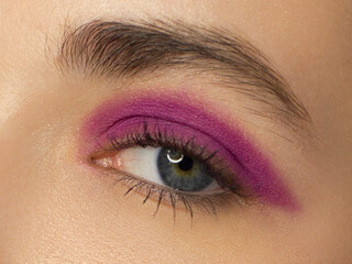Obraz premium Glamour close-up portrait of beautiful woman model face with winged purpule eyeliner make-up, clean skin on white background. Long eyelashes and thick eyebrows.