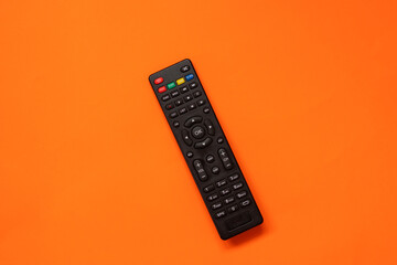 TV remote controller on orange background. Space for text. Top view