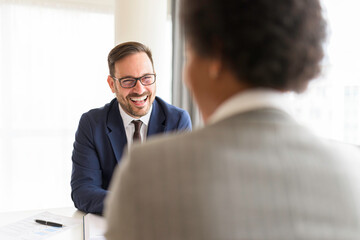 HR manager interviewing African-American female job candidate applicant and looking at her during Job Interview with huge smile on his face