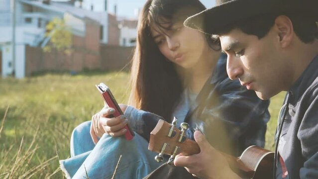 Mujer aprendiendo a tocar ukulele (Guitarra peque&ntilde;a) en un parque al atardecer.