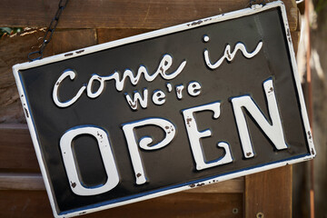 Sign on the front door of a store with the words Come in we are open - 502819605