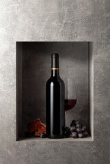 Bottle and glass of red wine with blue grapes.