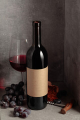 Bottle and glass of red wine with blue grapes.
