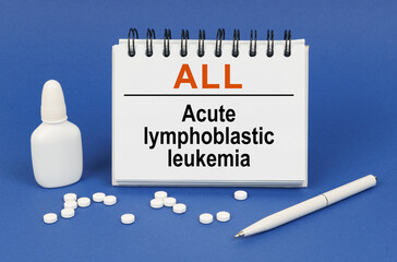 On a blue background, a pen, tablets and a notepad with the inscription - ALL Acute lymphoblastic...