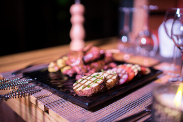 A plate of Chicken and beef BBQ with grilled tomatoes, potatoes and onions 