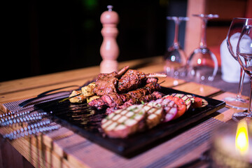 A plate of Chicken and beef BBQ with grilled tomatoes, potatoes and onions 