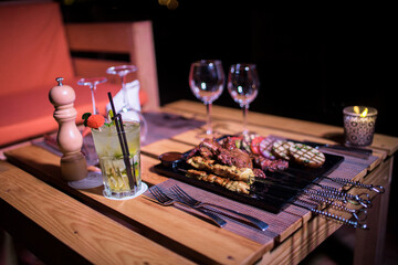 A plate of Chicken and beef BBQ with grilled tomatoes, potatoes and onions 