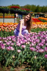 Obraz na płótnie Canvas A young woman in a pink suit stands in a blooming field of tulips. Spring time