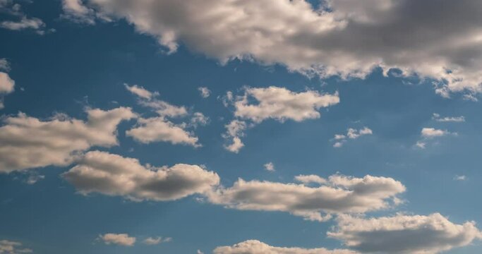 Time lapse clip of white fluffy rolling storm clouds over blue sky 