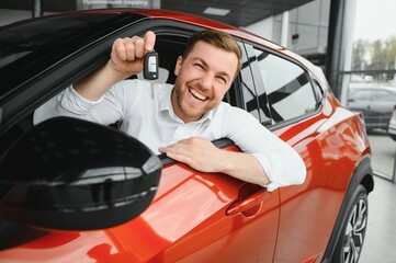 Happy man showing the key of his new car.