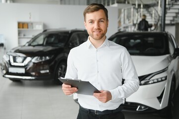 portrait of open-minded professional salesman in cars showroom, caucasian man in white formal shirt...