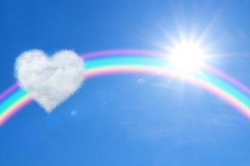 Beautiful view of heart shaped cloud, rainbow and sun in blue sky