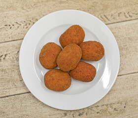 Six rice supplì on a white dish.
