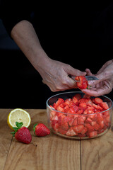 Female hands cutting strawberries. Vertical.