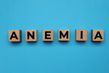 Obraz premium Wooden cubes with word Anemia on light blue background, flat lay